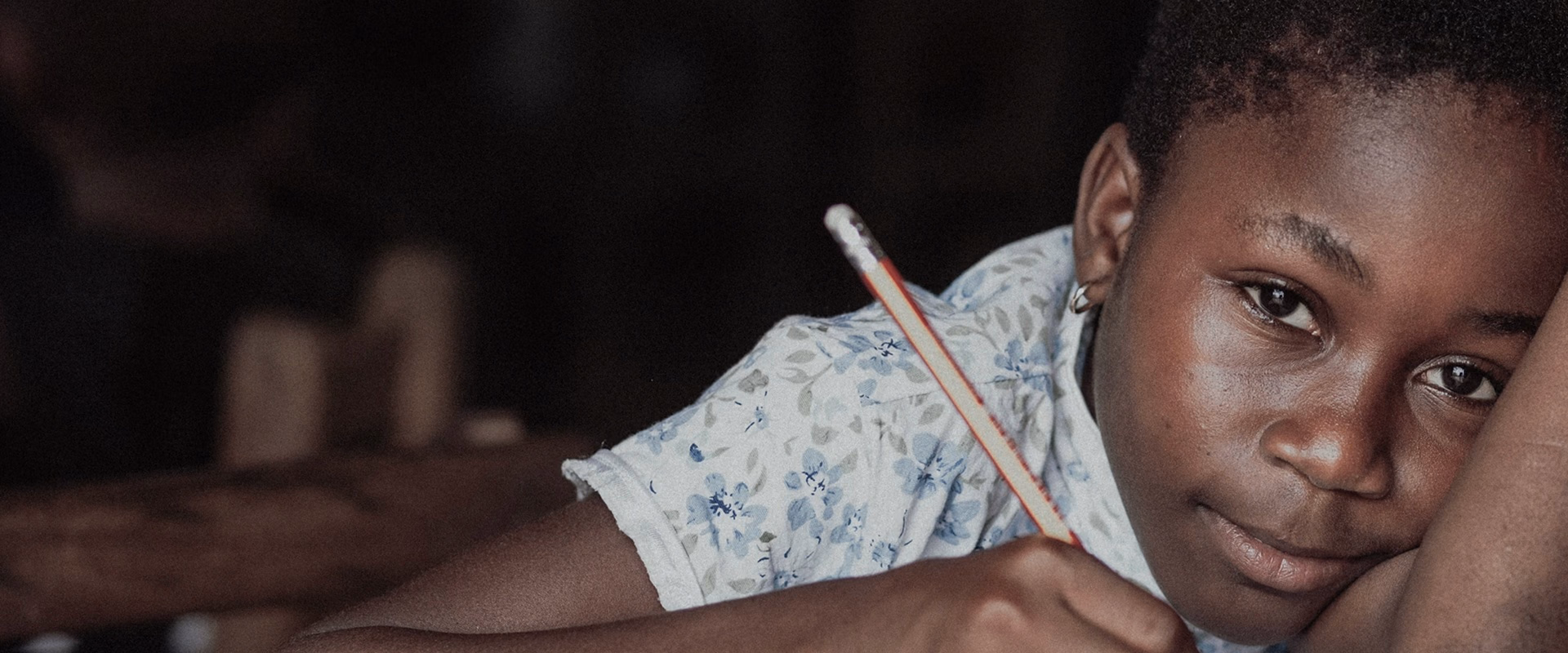 A young girl writing with a pencil