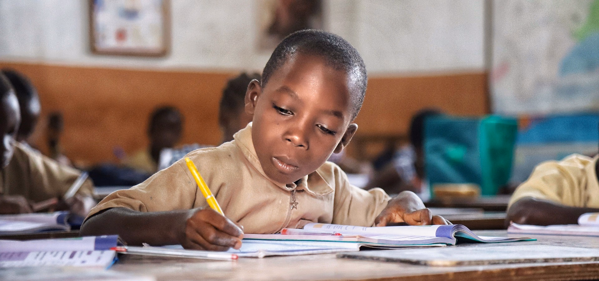 A student concentrating as he writes in a Ghanaian classroom